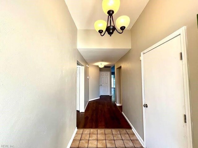 hall with a notable chandelier, light tile patterned flooring, and a towering ceiling