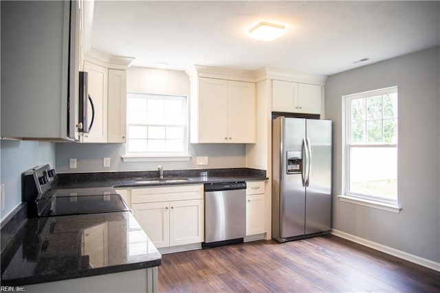 kitchen with dark stone counters, white cabinets, sink, dark hardwood / wood-style floors, and stainless steel appliances