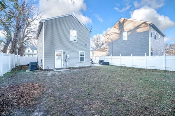 rear view of property with a yard and cooling unit