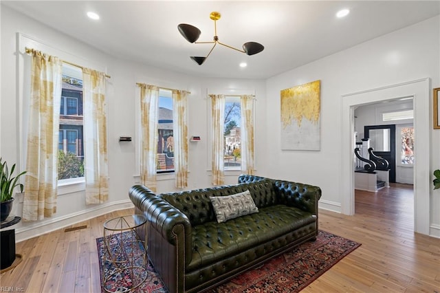 living room featuring a wealth of natural light, light hardwood / wood-style flooring, and an inviting chandelier