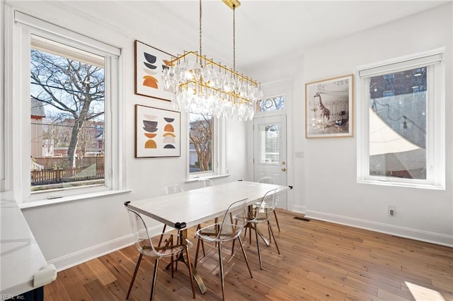 dining space featuring wood-type flooring and a notable chandelier