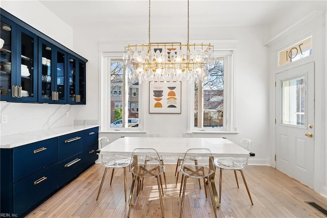 dining room with a notable chandelier, light wood-type flooring, and a wealth of natural light