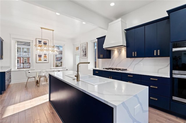 kitchen featuring pendant lighting, custom exhaust hood, light wood-type flooring, and a kitchen island with sink