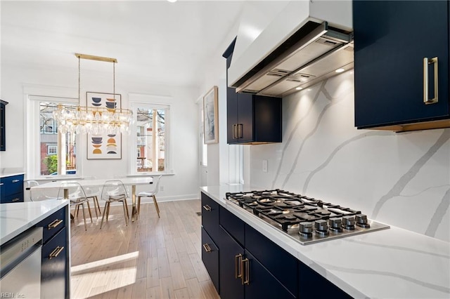 kitchen with light stone countertops, light hardwood / wood-style floors, decorative light fixtures, custom exhaust hood, and appliances with stainless steel finishes