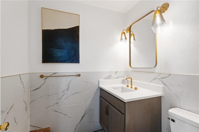 bathroom featuring vanity, toilet, and tile walls