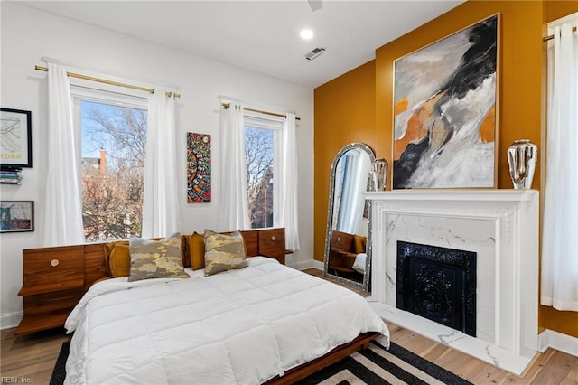 bedroom with a premium fireplace and wood-type flooring