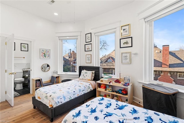 bedroom featuring ensuite bathroom, light hardwood / wood-style flooring, and multiple windows