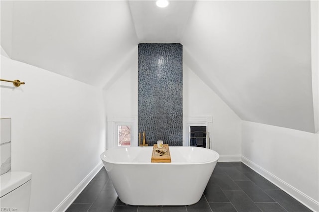 bathroom with a washtub, toilet, and lofted ceiling