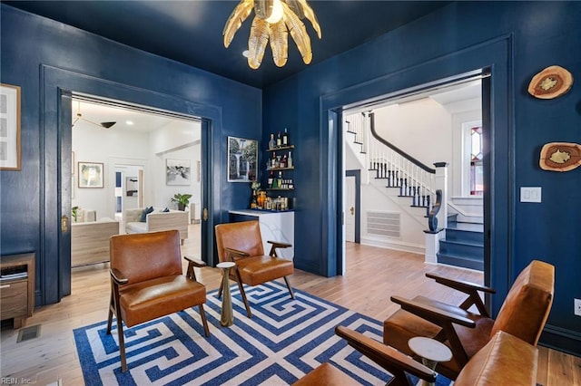 sitting room featuring bar, light hardwood / wood-style floors, and an inviting chandelier