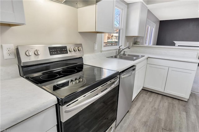 kitchen featuring kitchen peninsula, light wood-type flooring, stainless steel appliances, sink, and white cabinetry