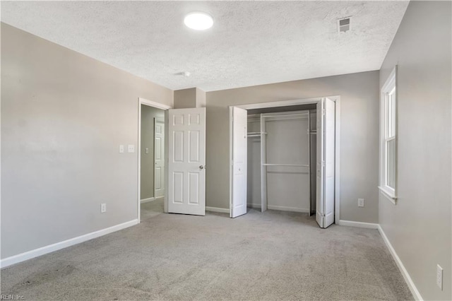 unfurnished bedroom featuring light carpet, a textured ceiling, and a closet