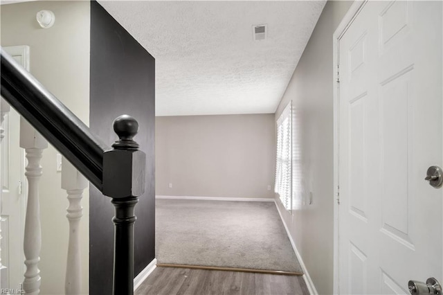 corridor with wood-type flooring and a textured ceiling