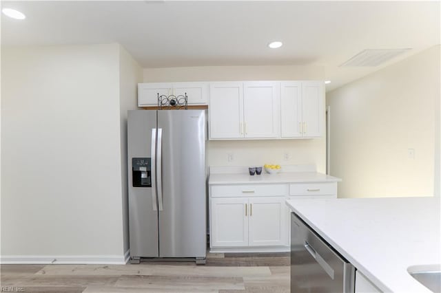 kitchen with white cabinets, light wood-type flooring, and appliances with stainless steel finishes