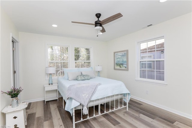 bedroom with hardwood / wood-style flooring, ceiling fan, and multiple windows