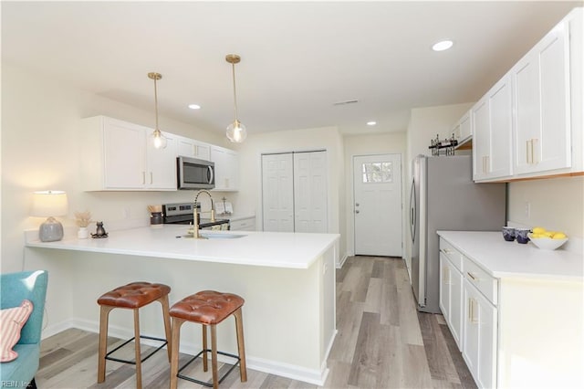 kitchen with white cabinetry, sink, stainless steel appliances, kitchen peninsula, and pendant lighting