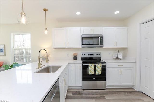 kitchen with white cabinetry, sink, hanging light fixtures, and appliances with stainless steel finishes