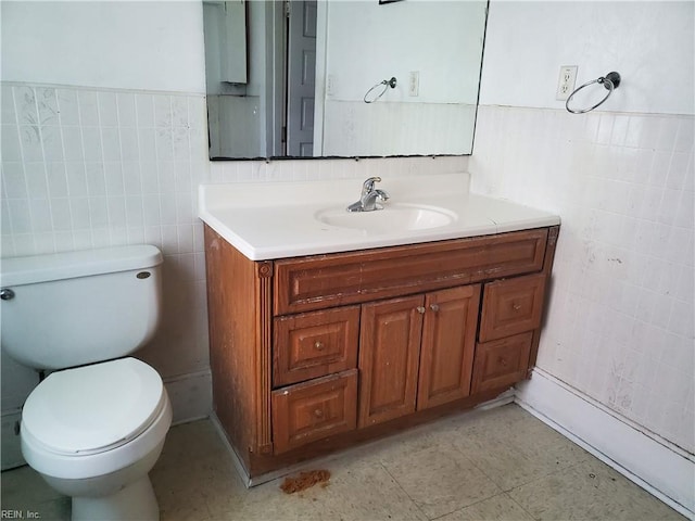 bathroom with vanity, toilet, and tile walls