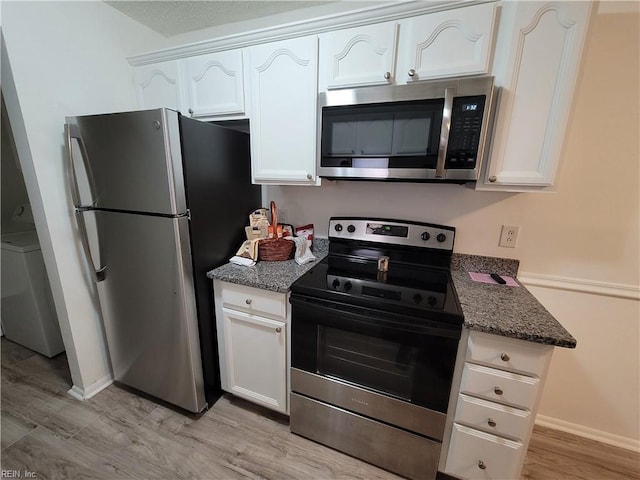 kitchen with light hardwood / wood-style flooring, dark stone countertops, washer / dryer, white cabinetry, and stainless steel appliances