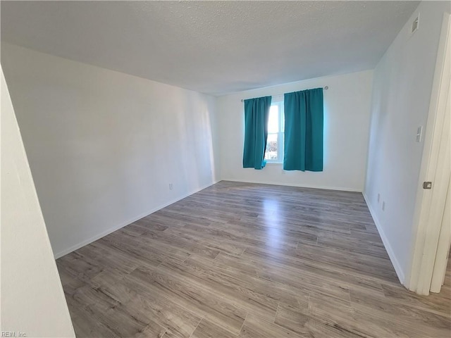 unfurnished room featuring wood-type flooring and a textured ceiling