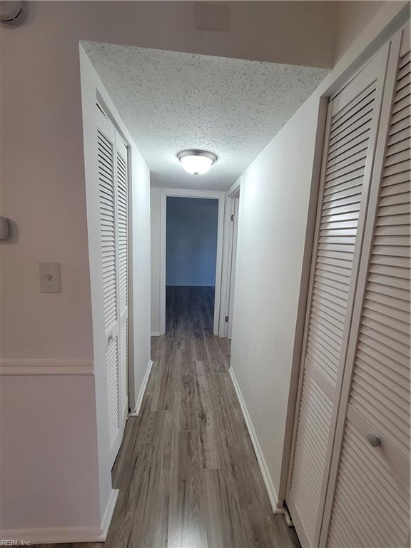 hallway featuring wood-type flooring and a textured ceiling