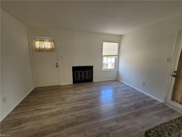 unfurnished living room featuring hardwood / wood-style floors and a textured ceiling