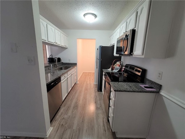 kitchen with sink, white cabinetry, stainless steel appliances, and light wood-type flooring