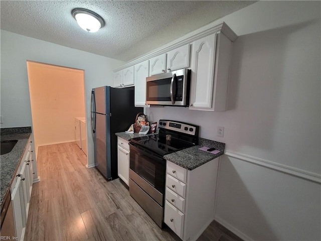 kitchen featuring dark stone countertops, independent washer and dryer, appliances with stainless steel finishes, light hardwood / wood-style floors, and white cabinetry