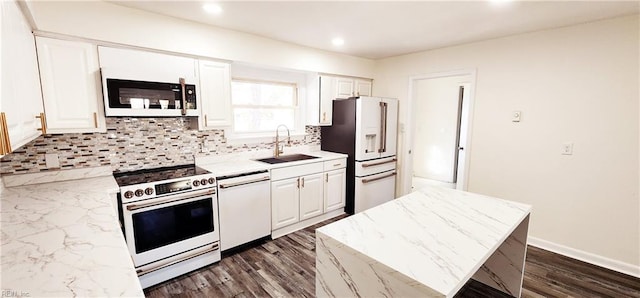 kitchen with white appliances, backsplash, sink, a kitchen island, and white cabinetry