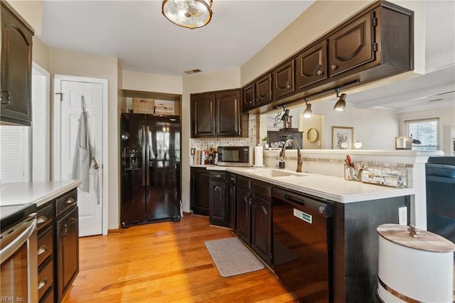 kitchen featuring sink, dark brown cabinets, black appliances, and light wood-type flooring