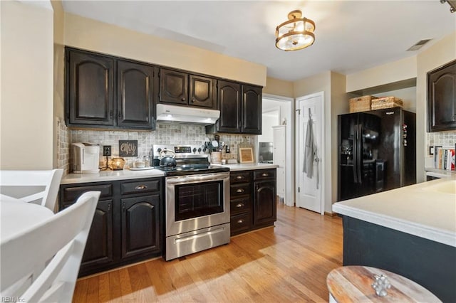 kitchen with dark brown cabinetry, black fridge, tasteful backsplash, stainless steel electric range oven, and light hardwood / wood-style floors