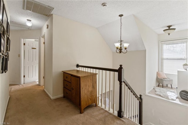 corridor featuring lofted ceiling, a chandelier, light carpet, and a textured ceiling