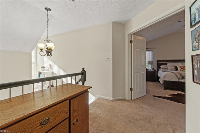 hall featuring an inviting chandelier, vaulted ceiling, light carpet, and a textured ceiling