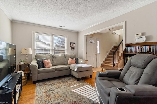 living room featuring ornamental molding, a textured ceiling, and light wood-type flooring