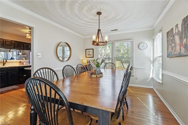 dining space featuring crown molding, sink, and light hardwood / wood-style flooring