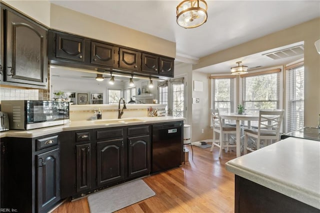 kitchen featuring sink, dark brown cabinets, light wood-type flooring, dishwasher, and backsplash