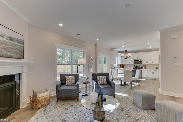 living room with a chandelier, light hardwood / wood-style flooring, and ornamental molding