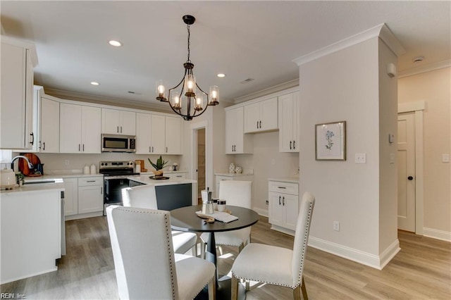 kitchen featuring ornamental molding, white cabinets, hanging light fixtures, and appliances with stainless steel finishes