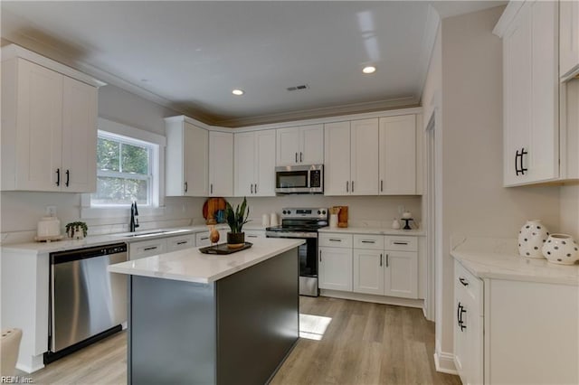 kitchen featuring stainless steel appliances, a kitchen island, sink, light hardwood / wood-style flooring, and white cabinetry