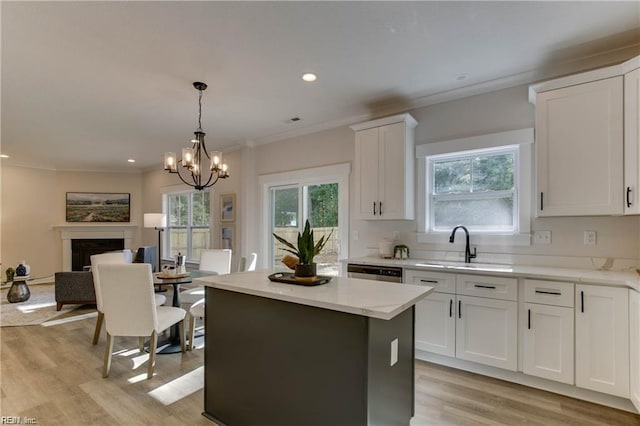 kitchen with a kitchen island, a chandelier, pendant lighting, white cabinets, and light wood-type flooring