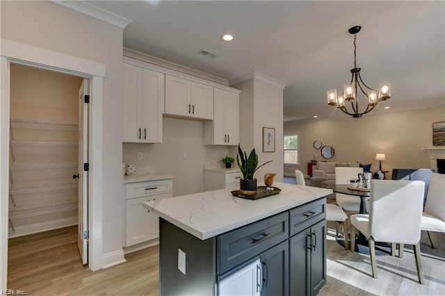 kitchen featuring a chandelier, a center island, light hardwood / wood-style floors, and white cabinetry