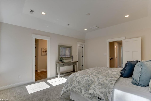 bedroom with carpet, a raised ceiling, and ensuite bath