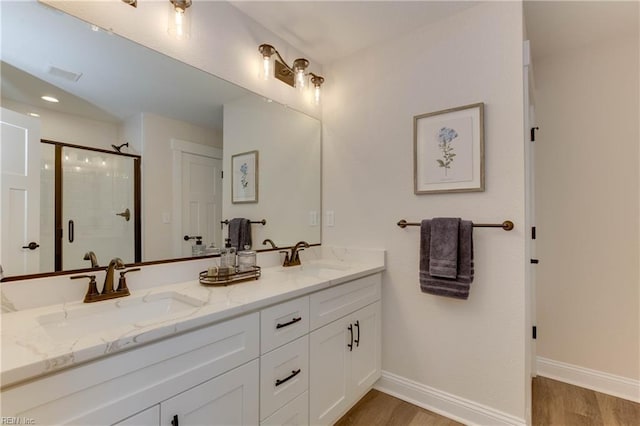 bathroom with hardwood / wood-style floors, vanity, and a shower with door