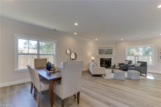 dining space with light wood-type flooring, plenty of natural light, and ornamental molding