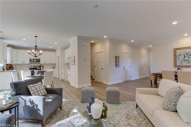 living room with light hardwood / wood-style floors, crown molding, a notable chandelier, and sink