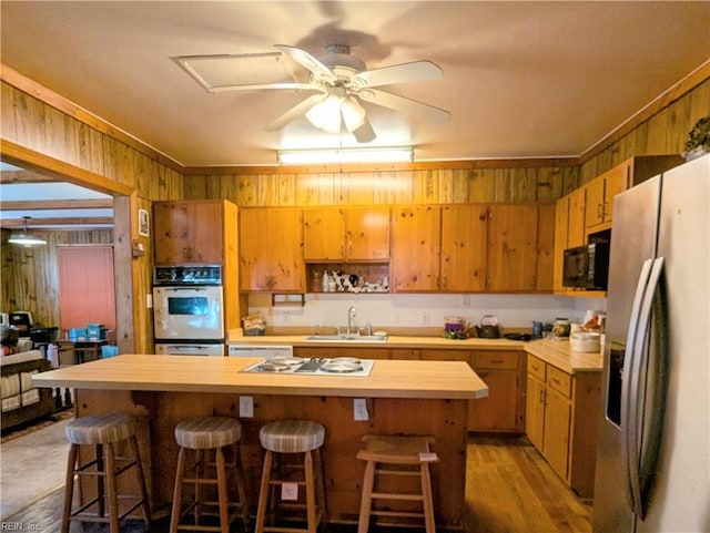 kitchen featuring stainless steel refrigerator with ice dispenser, wood counters, sink, and a kitchen island