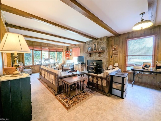 living room with a wood stove, beam ceiling, and wood walls