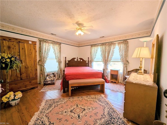 bedroom with ceiling fan, crown molding, wood-type flooring, and a textured ceiling