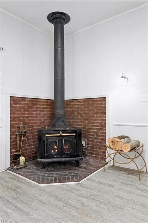 interior details featuring a wood stove, ornamental molding, and wood finished floors