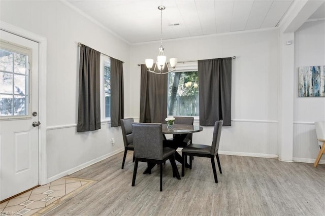 dining area with a notable chandelier, wood finished floors, visible vents, baseboards, and ornamental molding