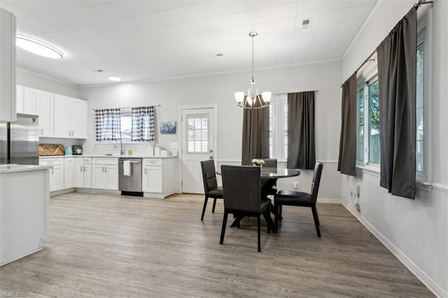 dining room featuring an inviting chandelier, ornamental molding, light wood finished floors, and a wealth of natural light